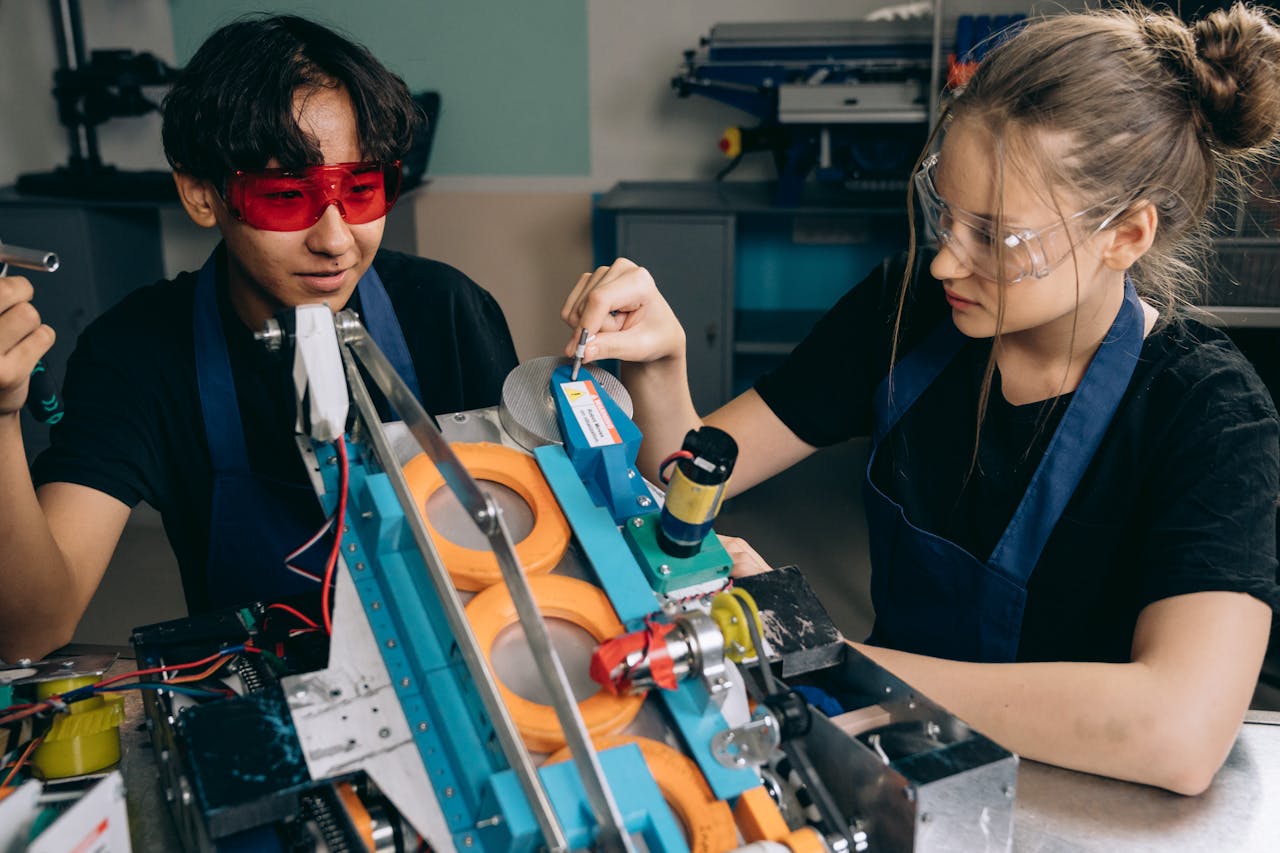 Two students collaborating on a robotics project in a tech lab, focusing on machinery details.